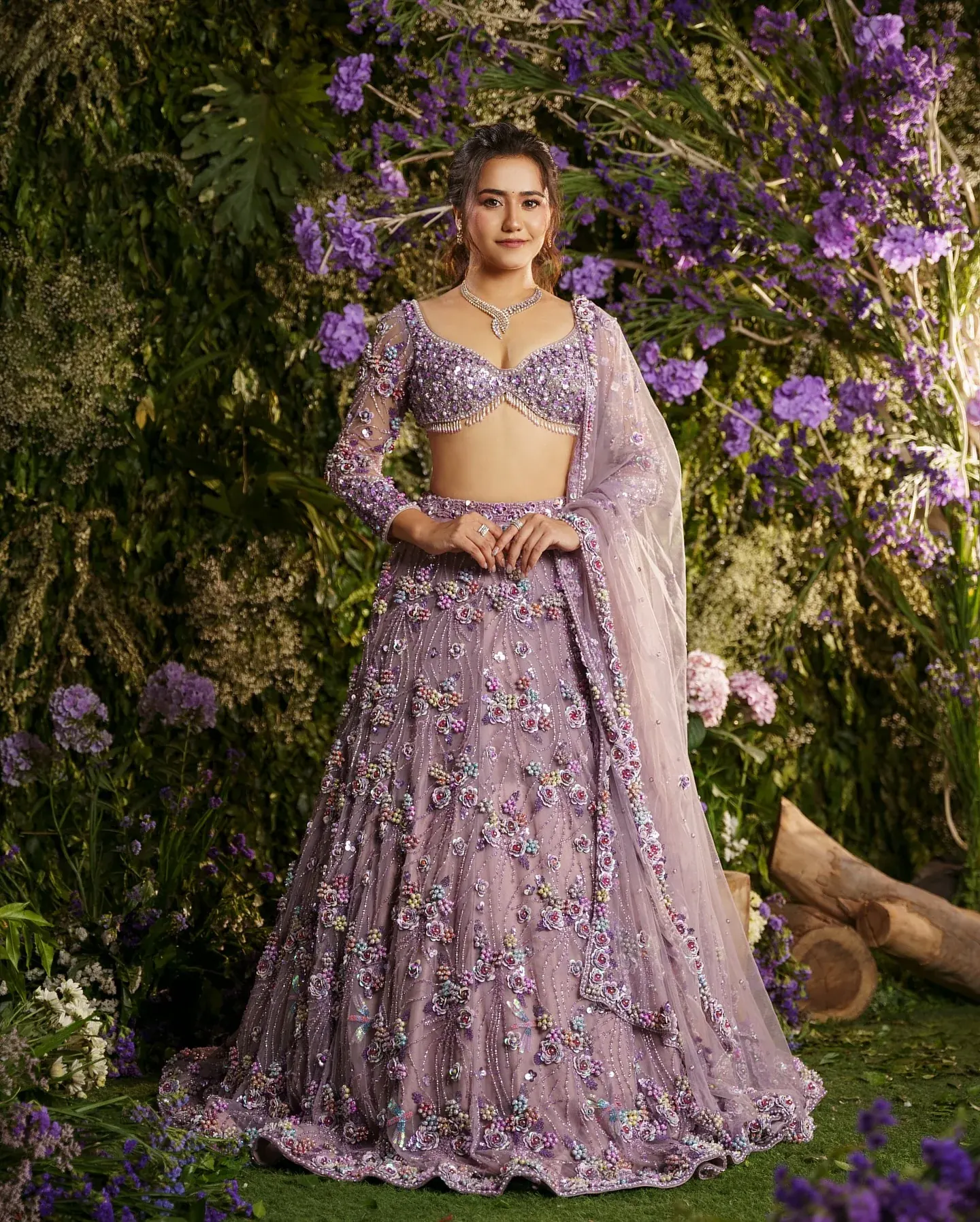 A lilac lehenga with bead work and a sheer dupatta, photographed among purple blooms.