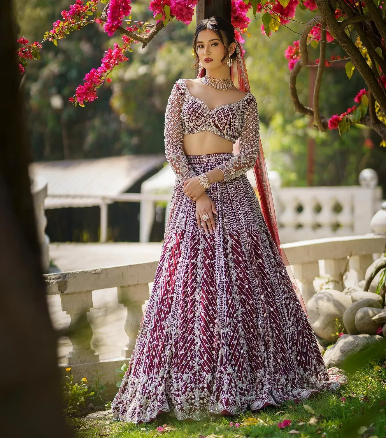 A mauve lehenga with striped bead work and a sheer dupatta, beside a white balustrade.