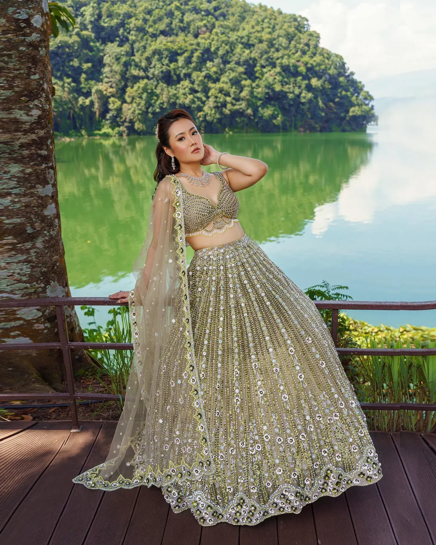 A champagne lehenga with sequin embroidery and a sheer dupatta, beside open water.