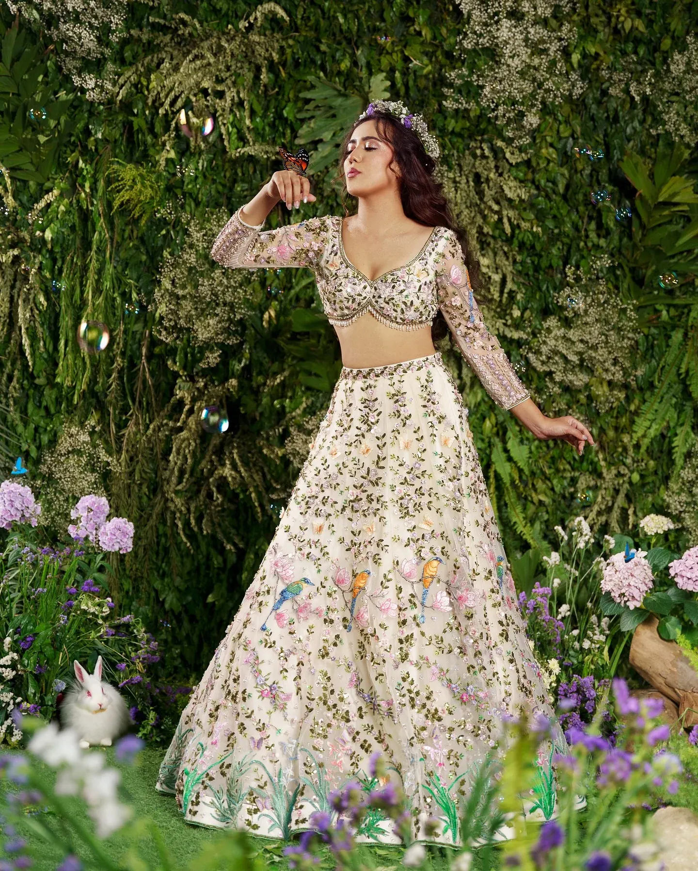 An ivory lehenga with coloured floral embroidery, photographed among flowers.