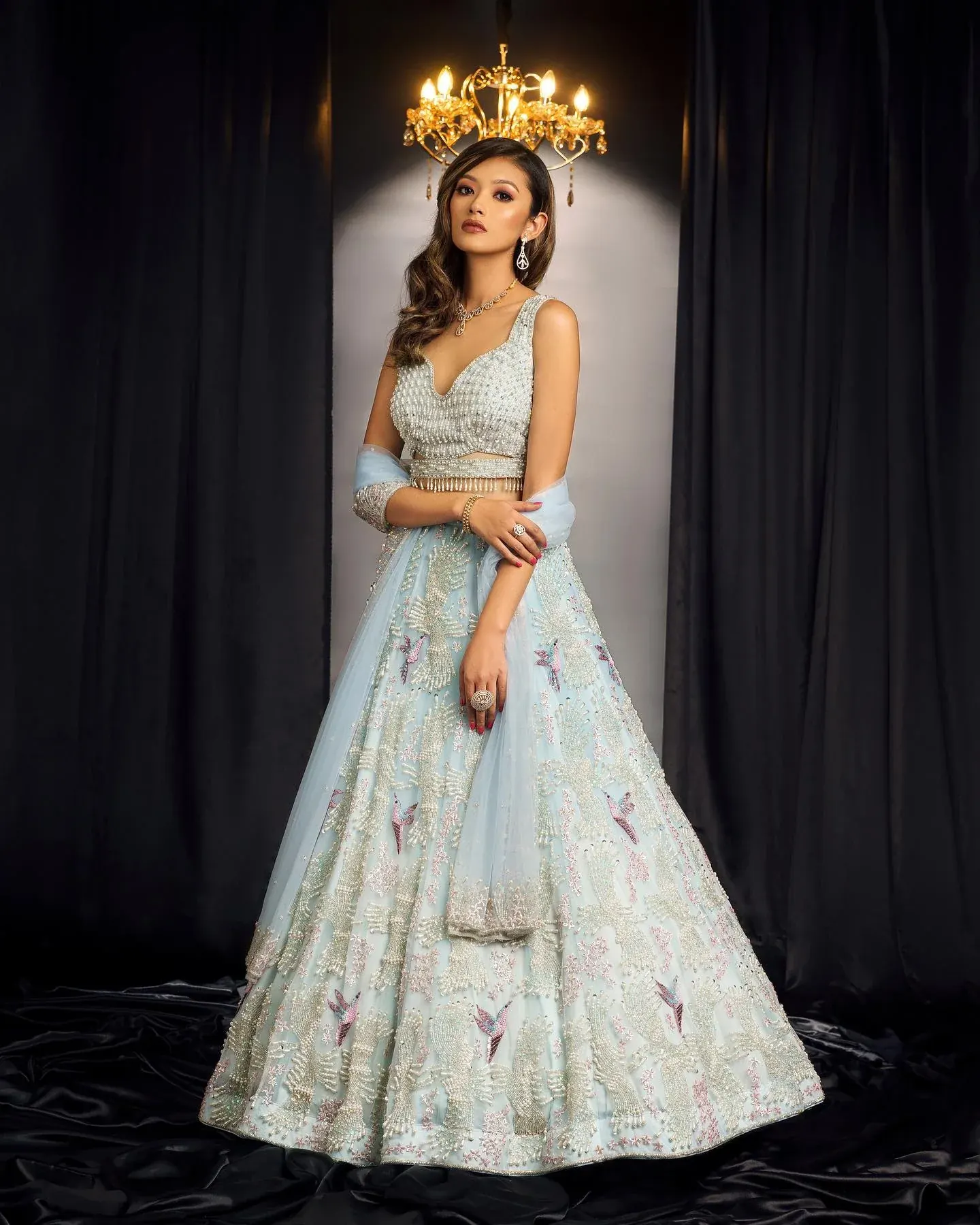 A pale blue lehenga with a scalloped hem, photographed beneath a chandelier.