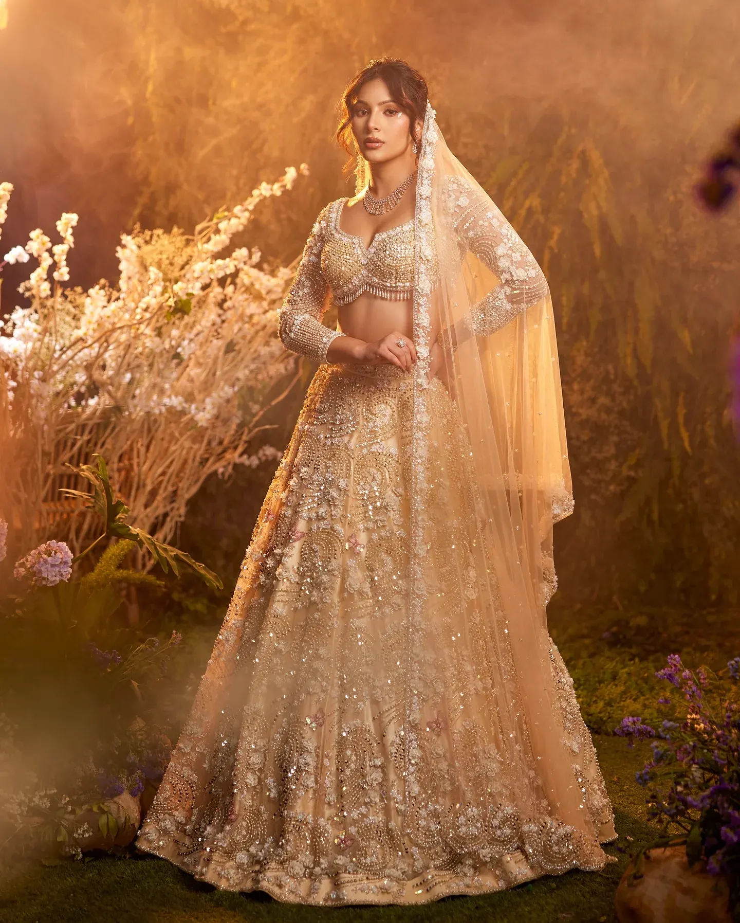 An ivory lehenga with a sheer dupatta and beaded blouse, among dried flowers.