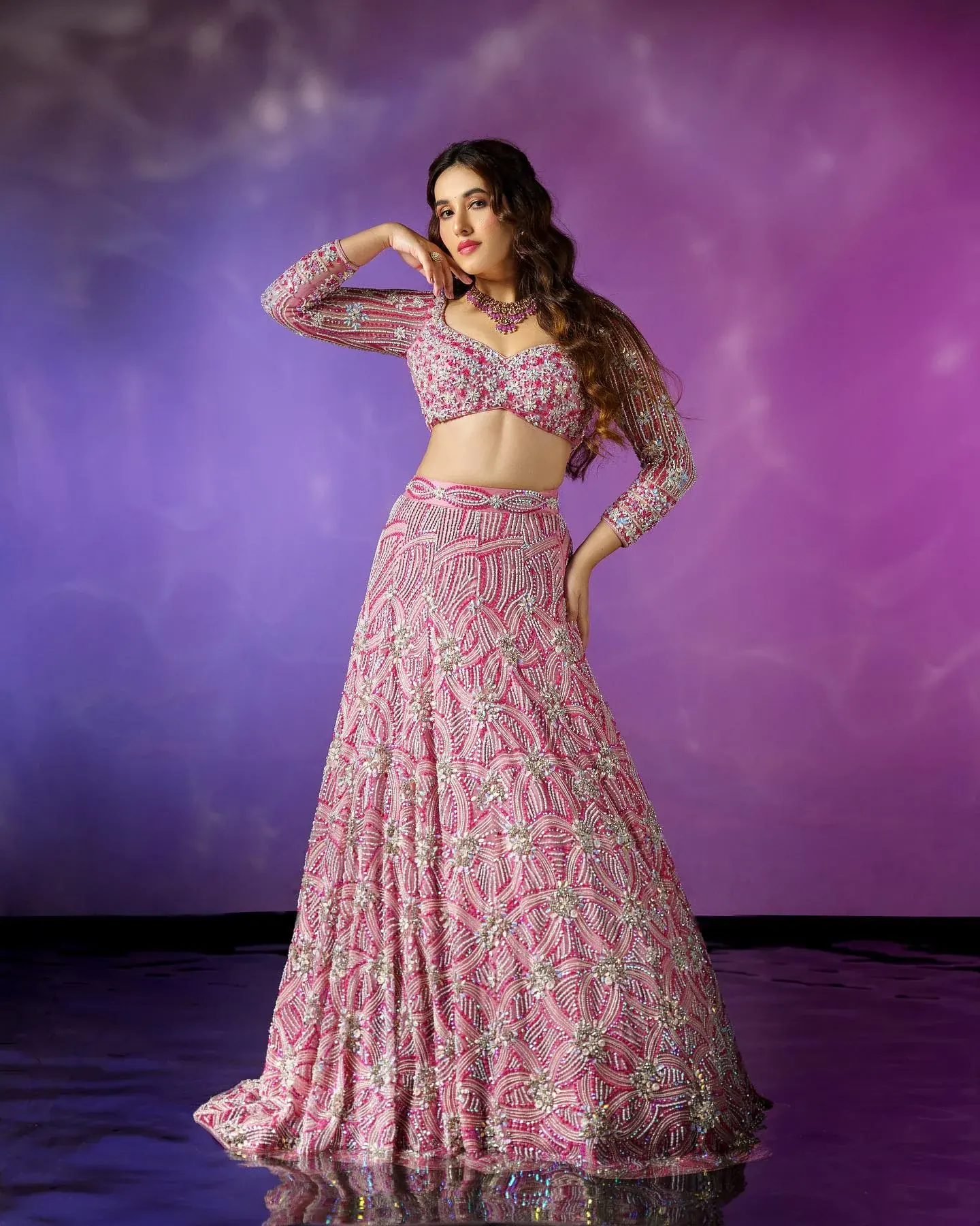 A pink lehenga with sequinned embroidery, photographed against a violet ground.