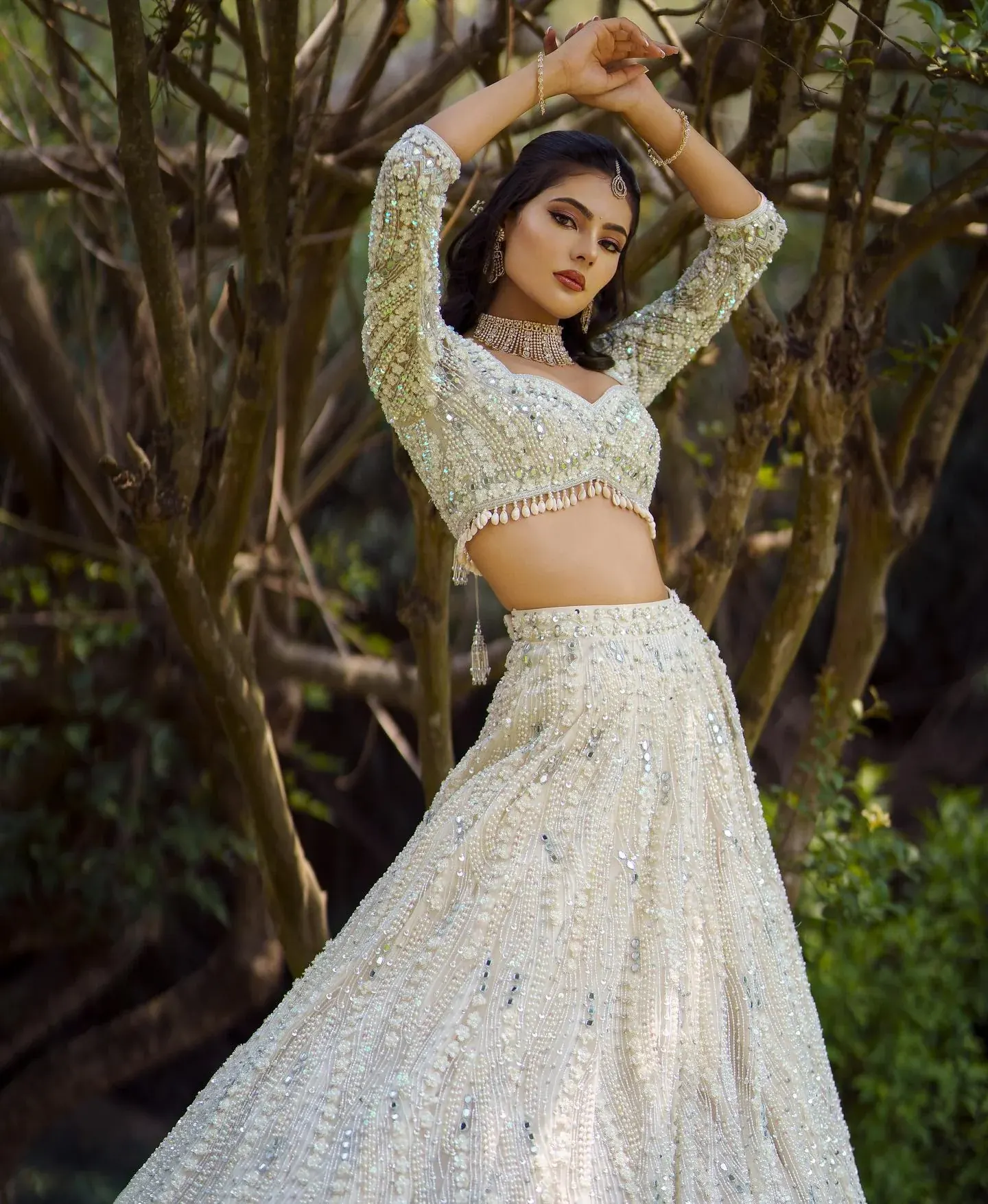 An ivory lehenga with sequinned embroidery, photographed in a bamboo grove.