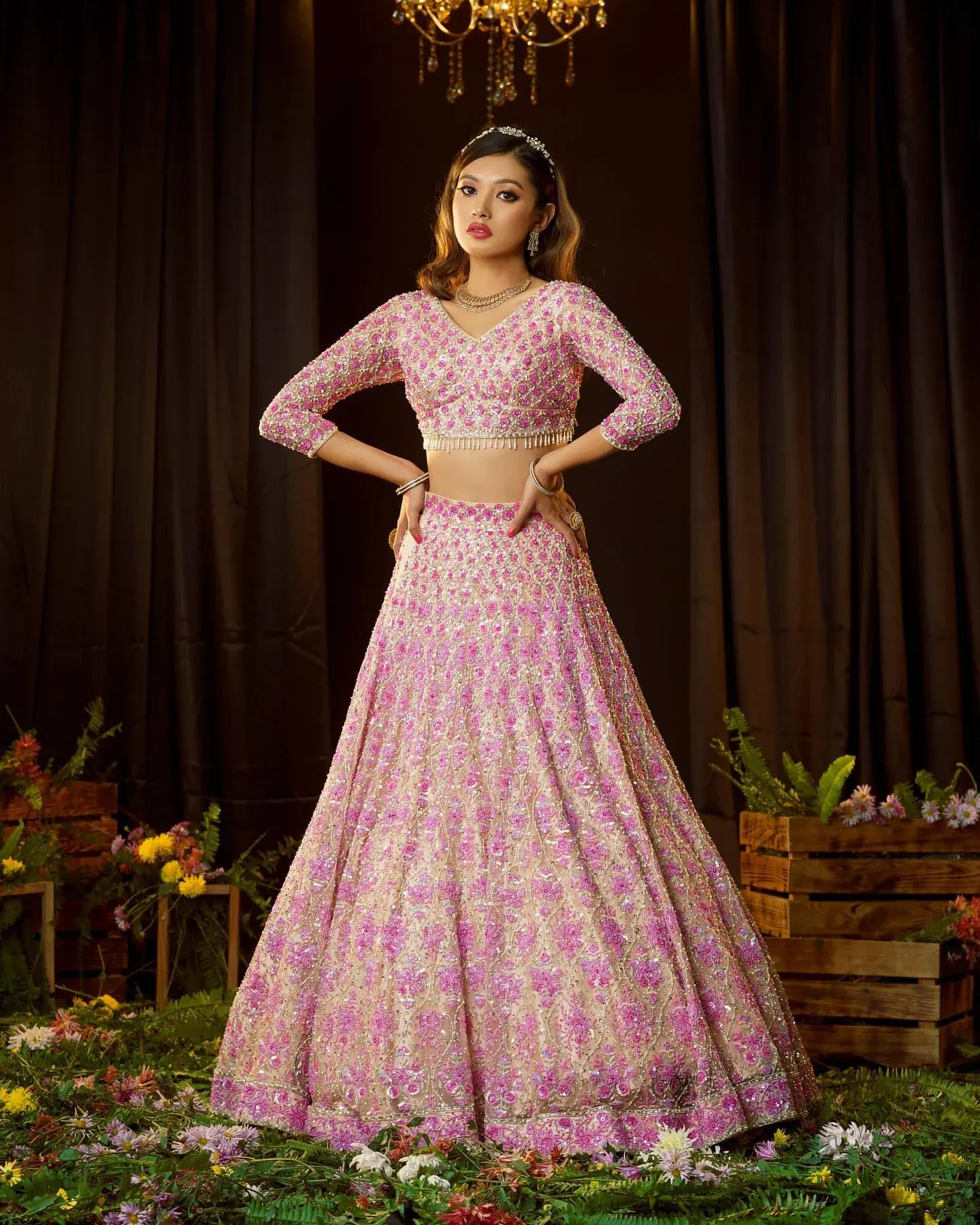 A pink lehenga with gold embroidery, photographed among flower crates.