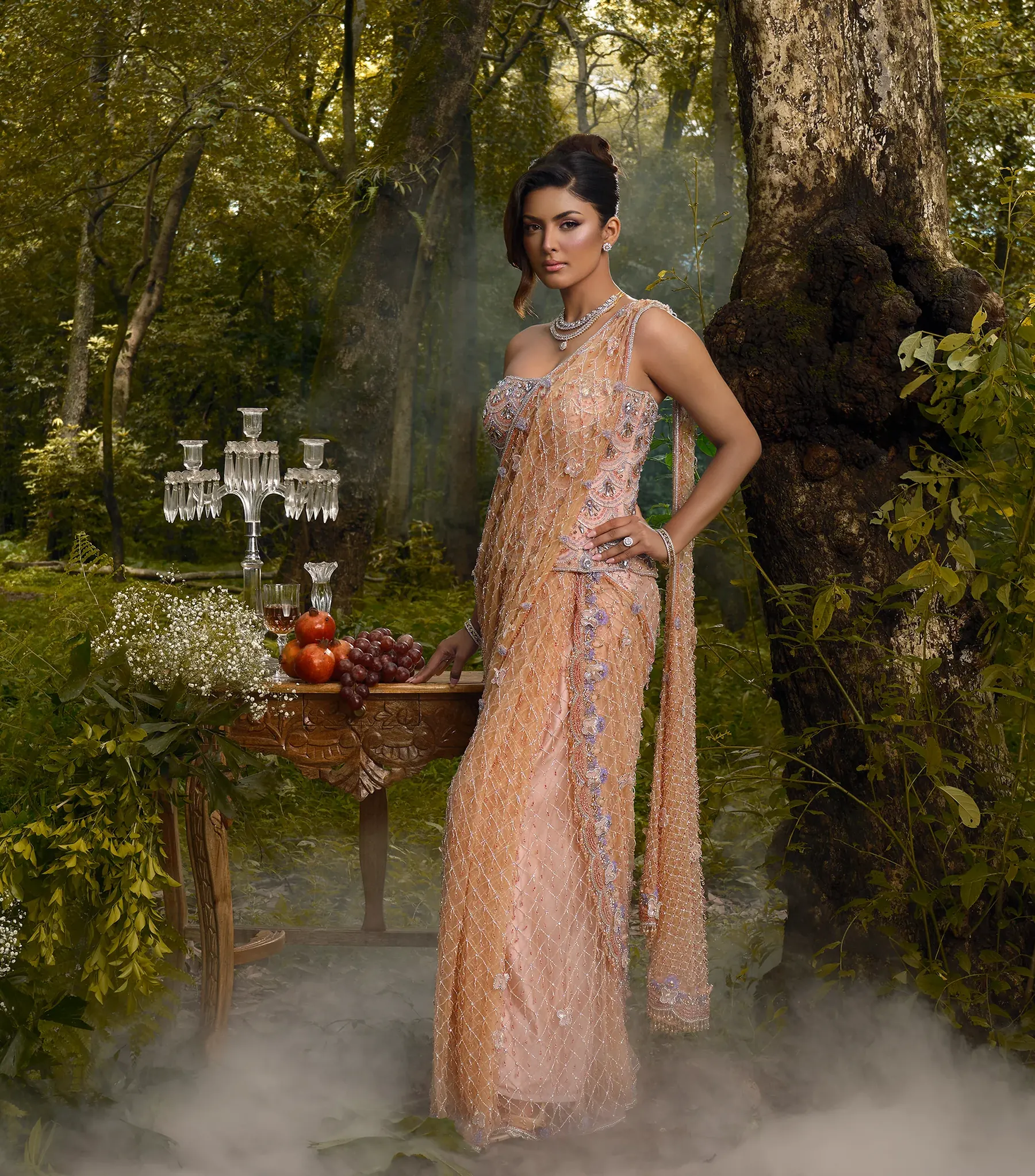 A peach net saree with silver embroidery and a beaded blouse, beside a carved table and a crystal candelabra.